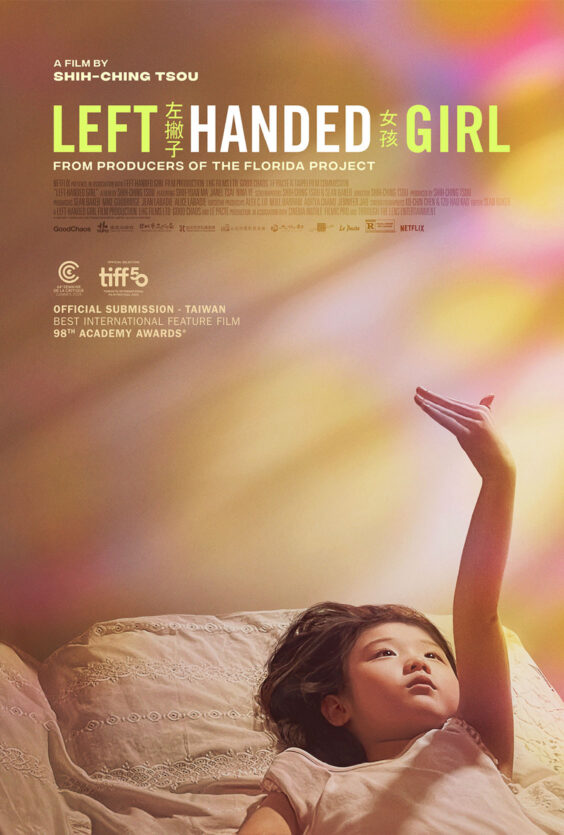 Left Handed Girl NY 2. Plakaten viser en ung jente som ligger i sengen og strekker venstre arm opp. Teksten på plakaten er "LEFT HANDED GIRL". Bakgrunnen er lys og fargerik.