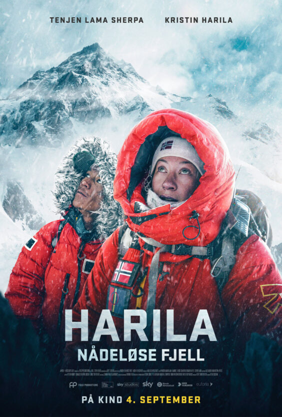 Harila Nådeløse Fjell To personer i røde dunjakker med hette og norske flagg står foran snødekte fjell Begge ser oppover Snø og fjell i bakgrunnen