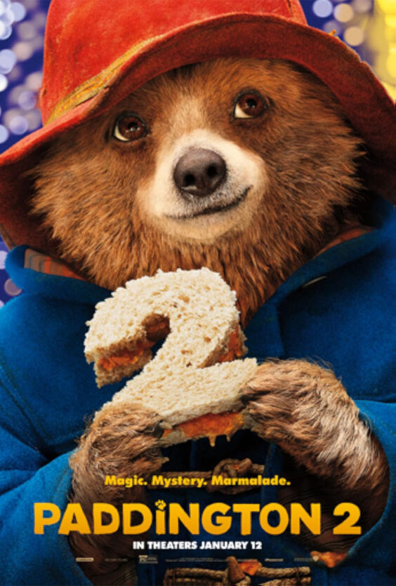 Paddington 2 En brun bjørn med rød hatt og blå jakke holder en sandwich formet som tallet to foran seg